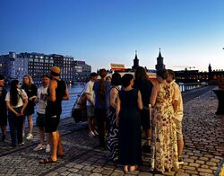 Kolleg: innen unterhalten sich miteinander am Sommerabend am Ufer